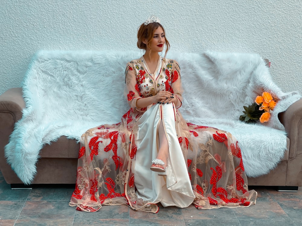 a woman sitting on a couch in a red and white dress