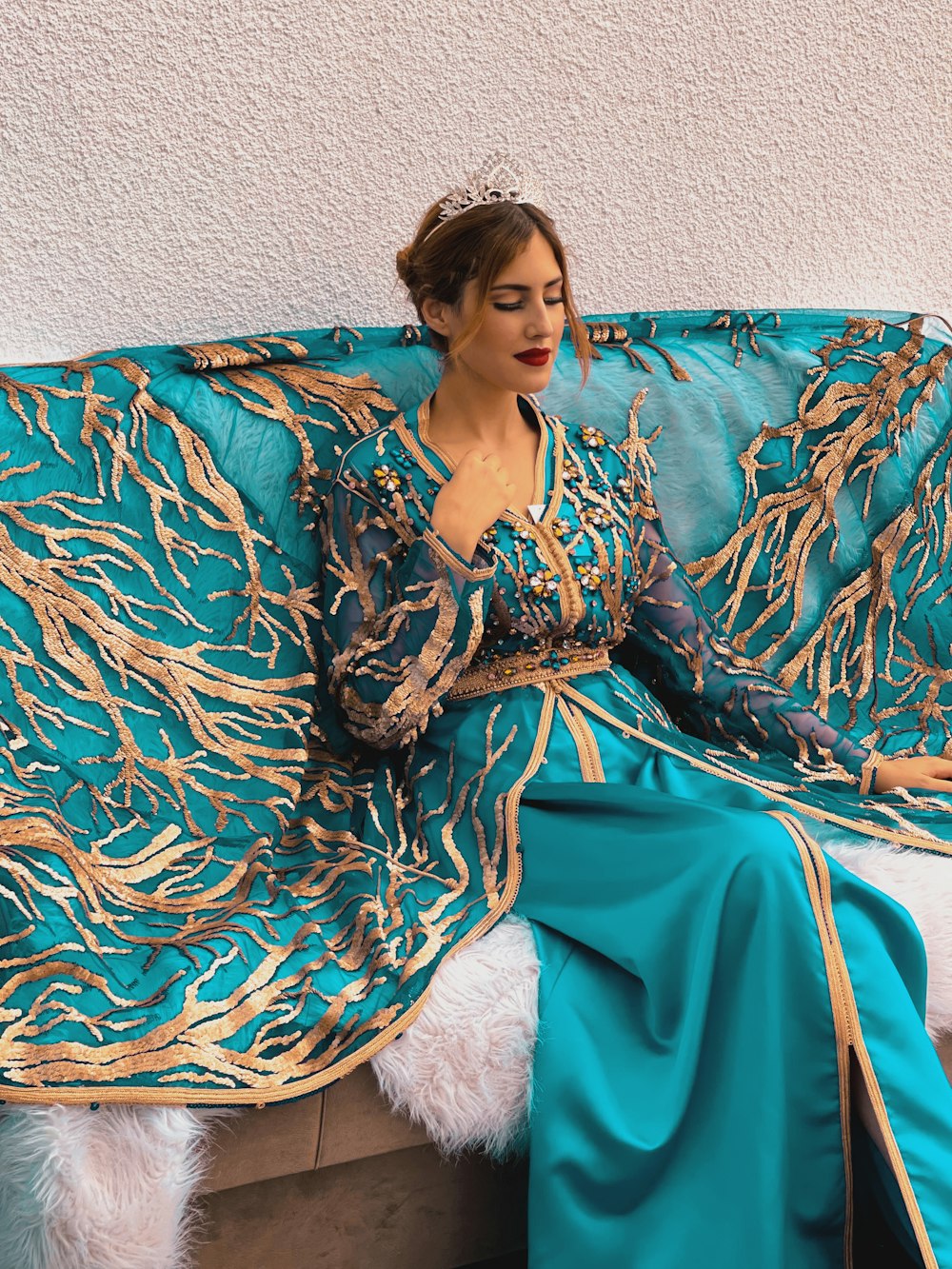 a woman sitting on a couch wearing a blue dress