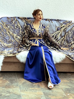 a woman in a blue dress sitting on a couch