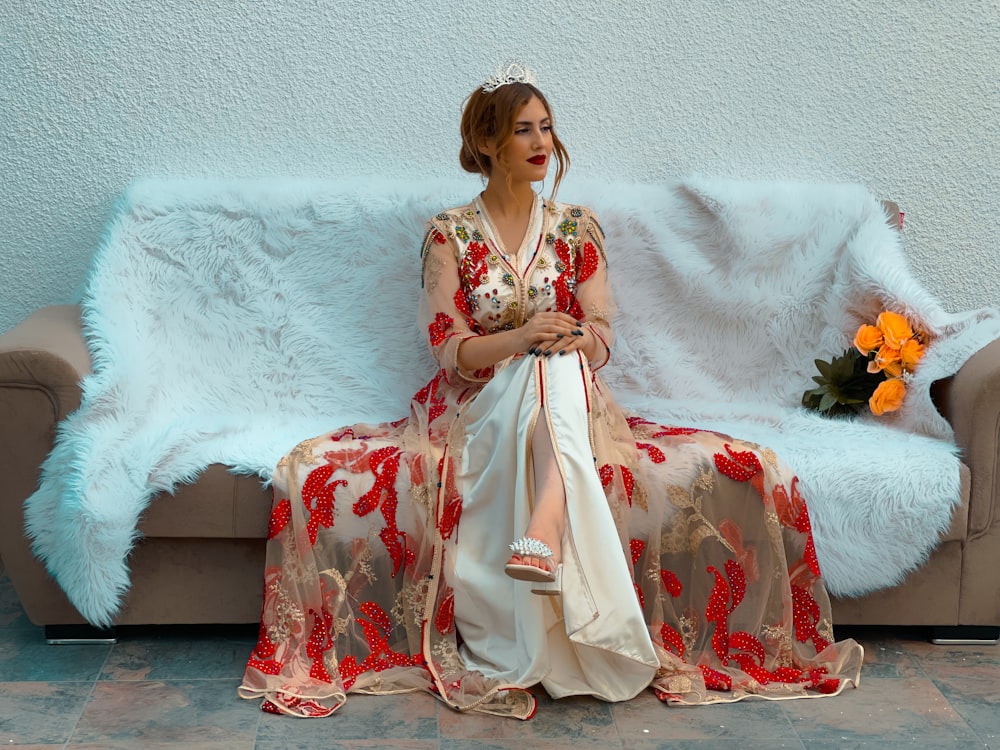 a woman sitting on a couch wearing a dress