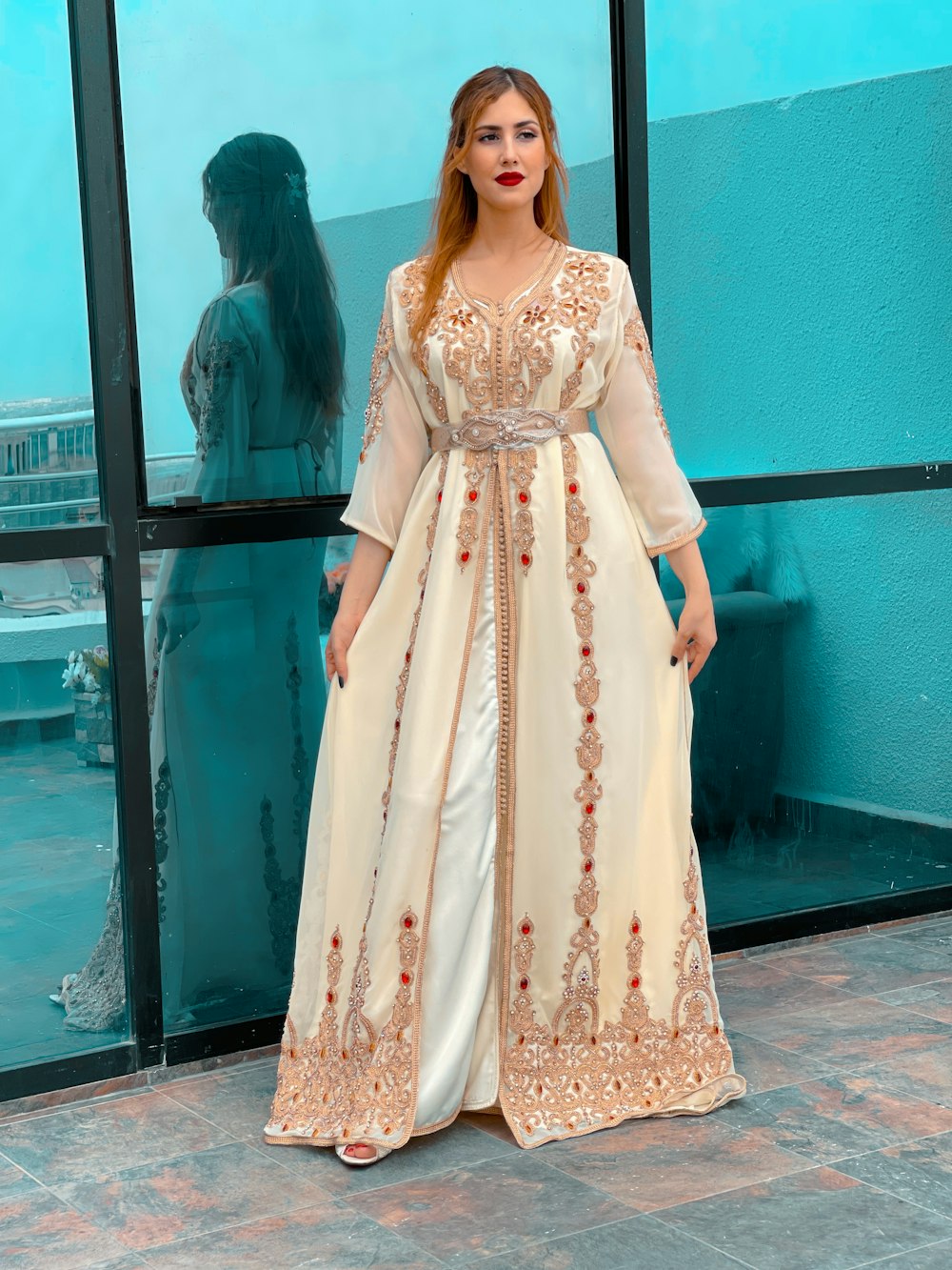 a woman standing in front of a window wearing a long dress