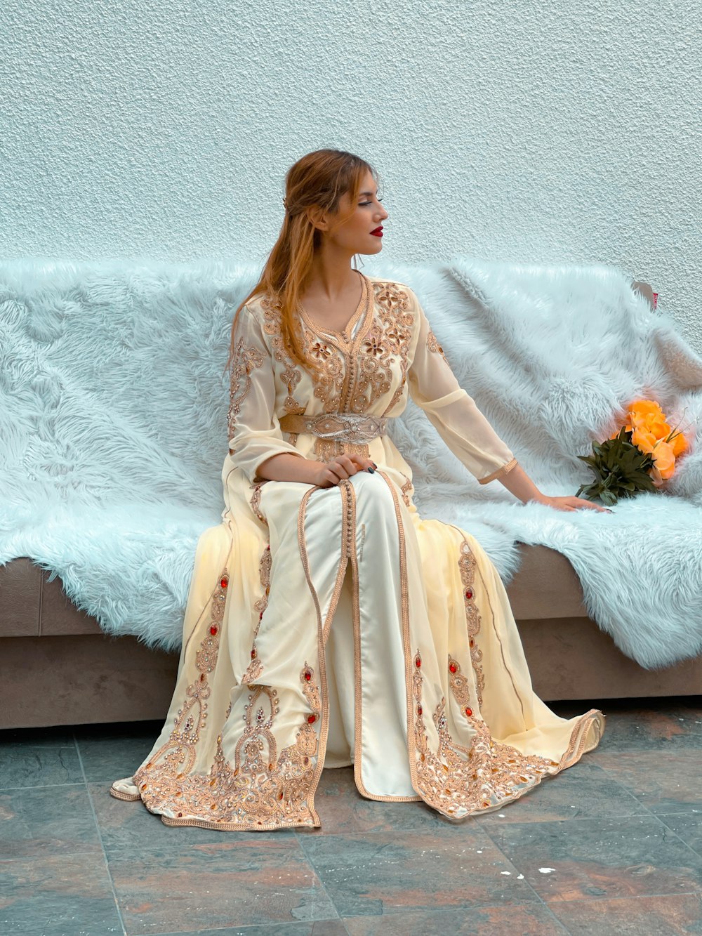a woman sitting on a couch wearing a long dress