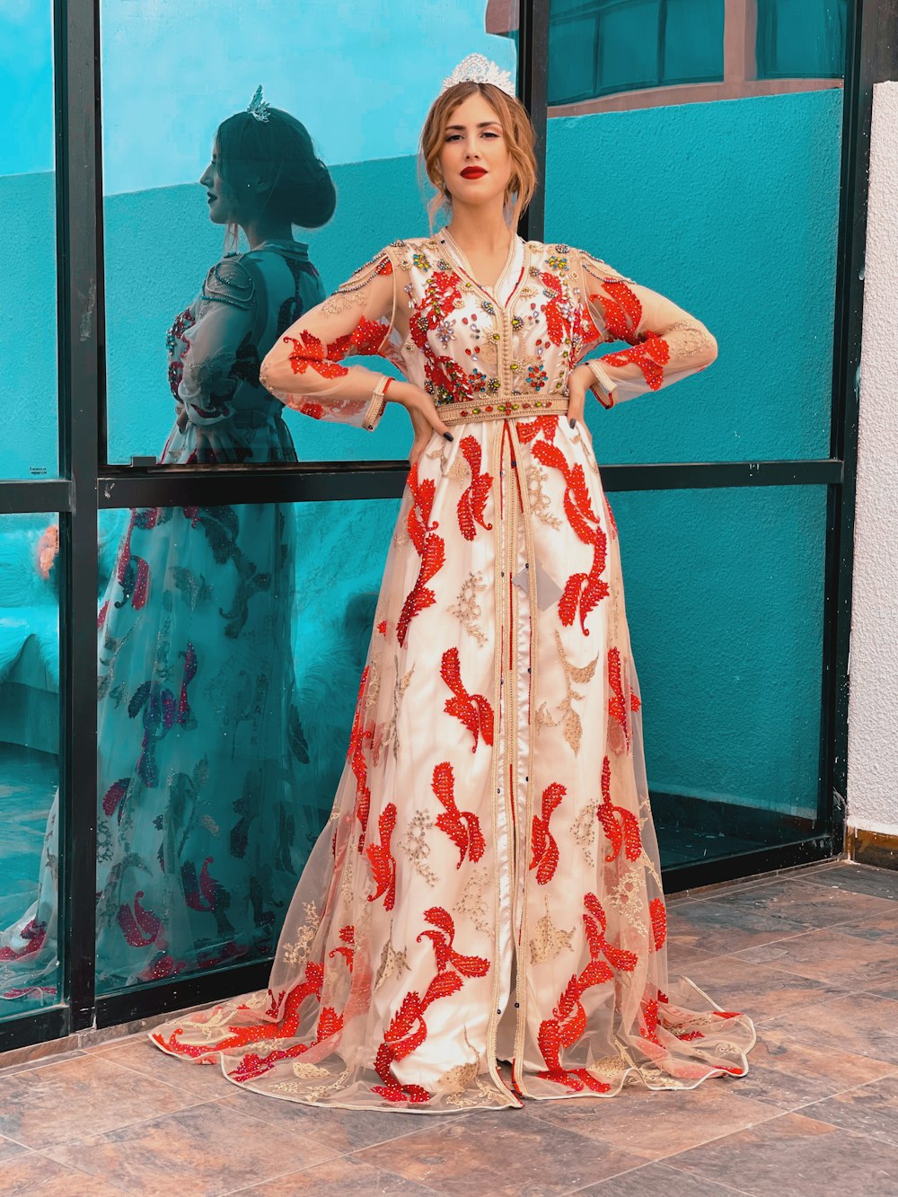 a woman standing in front of a window wearing a long dress