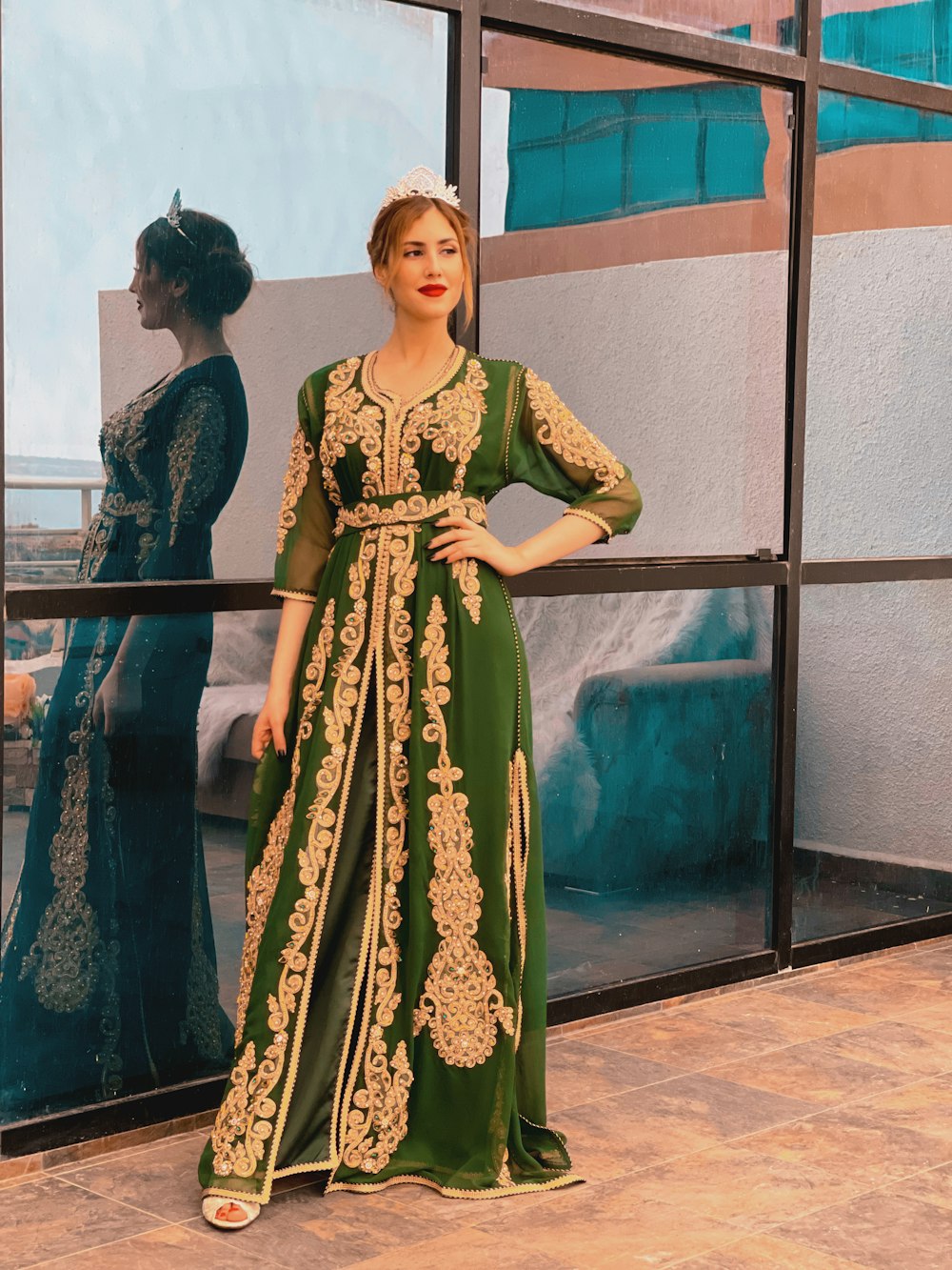 a woman standing in front of a window wearing a green dress