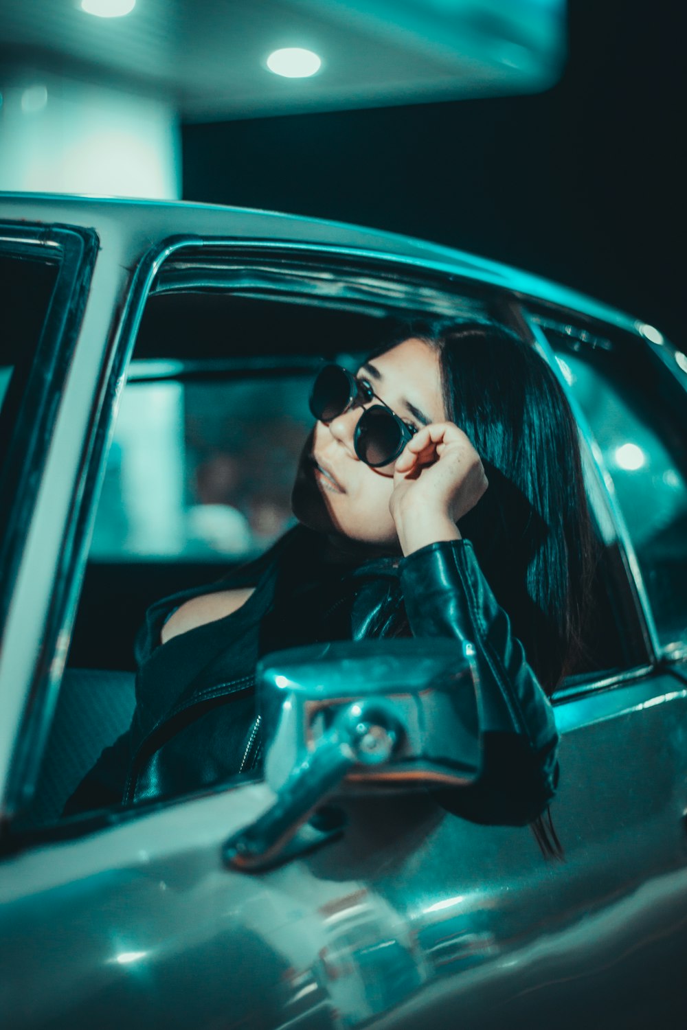 a woman in a leather jacket leaning out of a car window