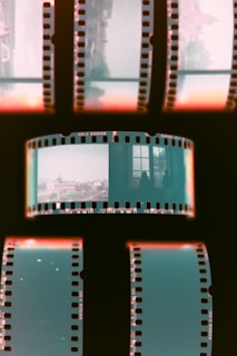 A strip of photographic film with several frames. Some frames contain images of urban or architectural scenes, while others are blank or dark. The surrounding film strip has visible edges with perforations typical of 35mm film.
