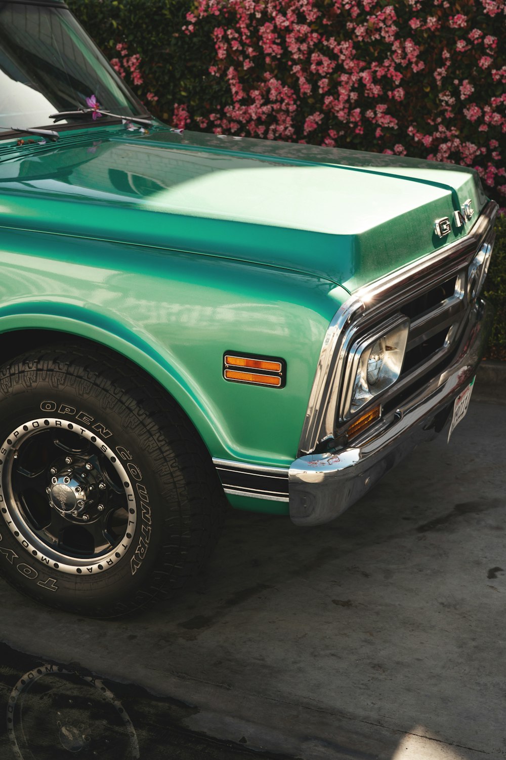 a green pick up truck parked next to a bush