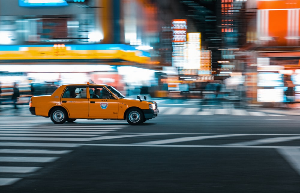 a yellow taxi cab driving down a city street