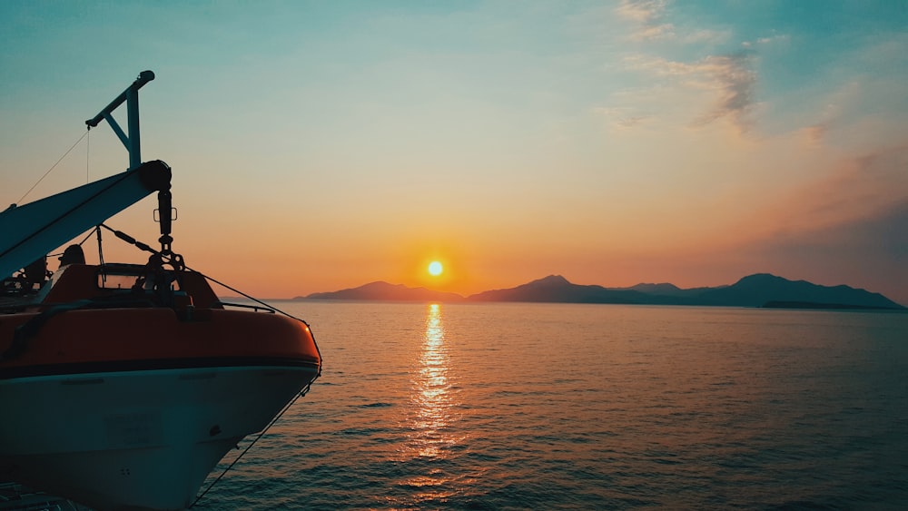 a boat in the water with the sun setting in the background