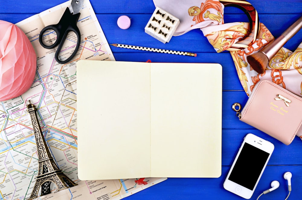 a table with a notebook, cell phone and other items