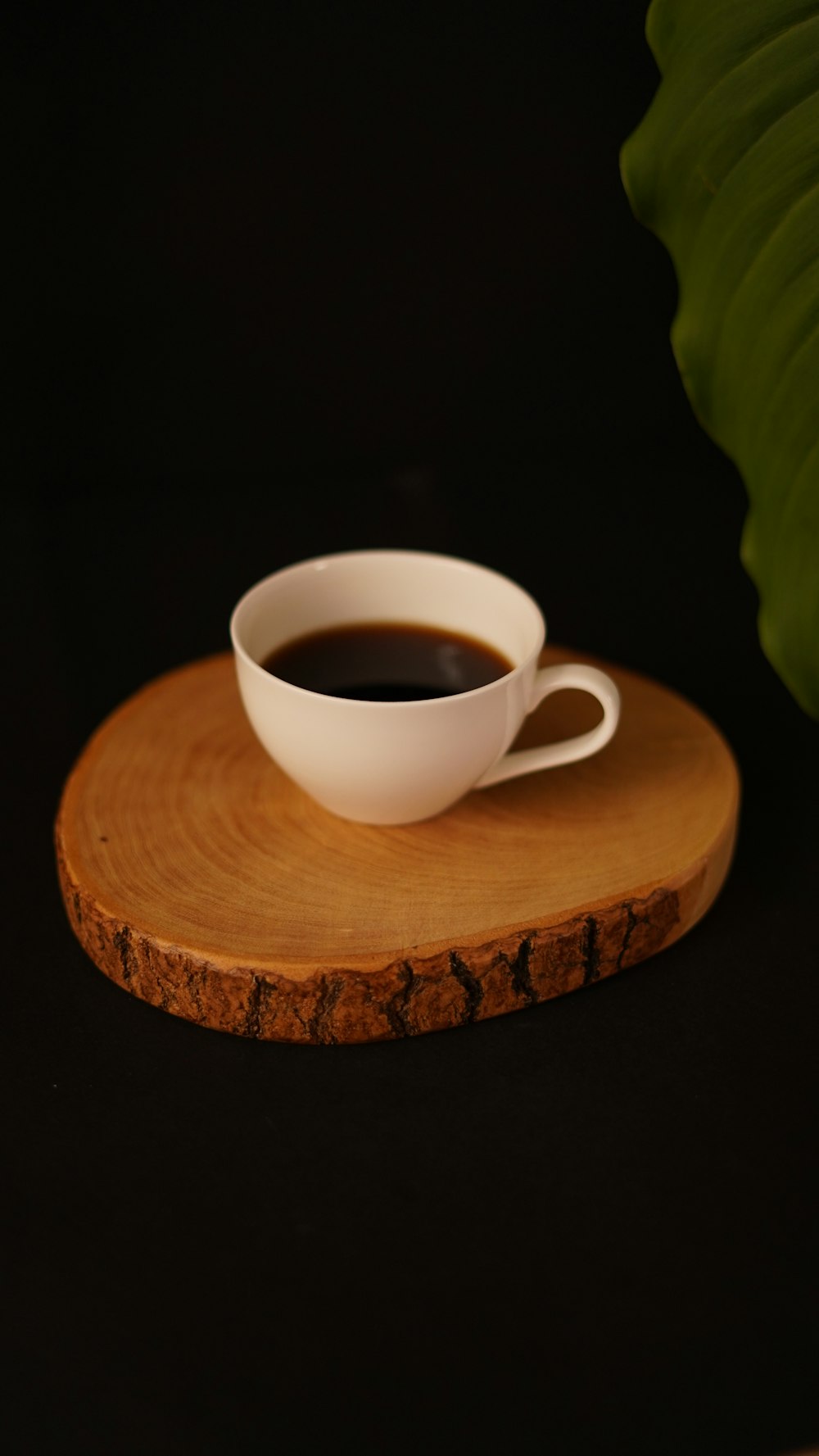 a cup of coffee sitting on top of a wooden coaster