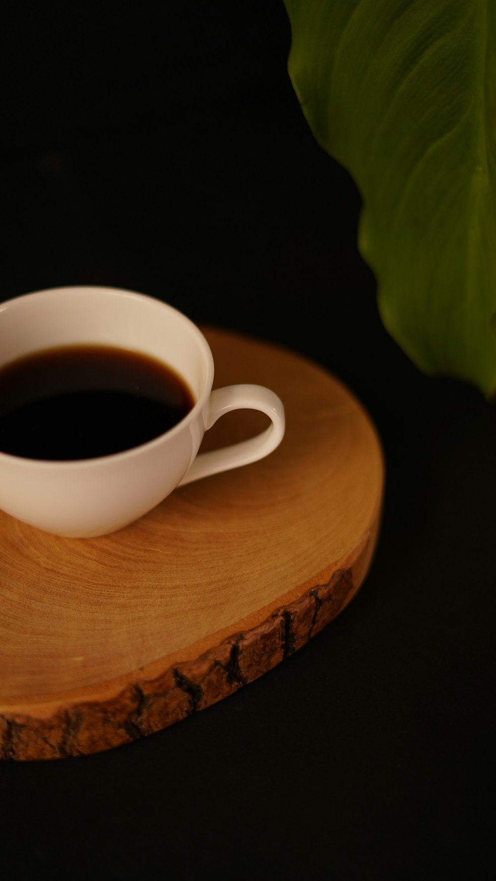 a cup of coffee sitting on top of a wooden coaster