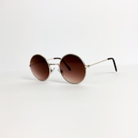 Elegant pair of sunglasses with dark lenses and thin golden frames under natural light.
