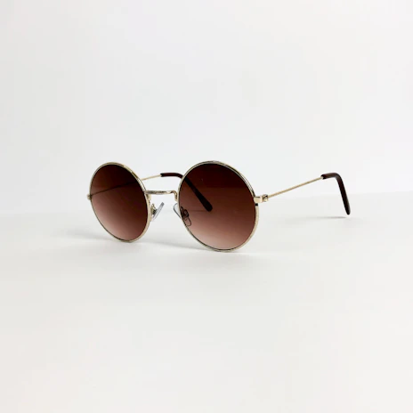 A pair of elegant sunglasses with thin metal frames placed on a soft beige fabric background.