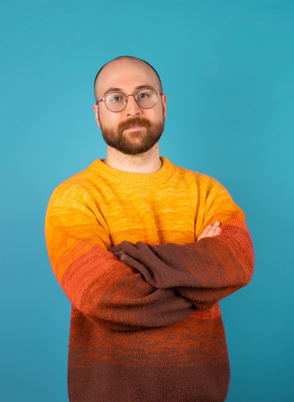 a man with a beard and glasses standing with his arms crossed