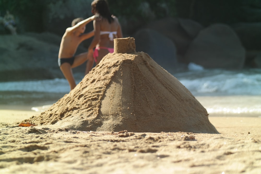 a sand castle on a beach with a woman in the background