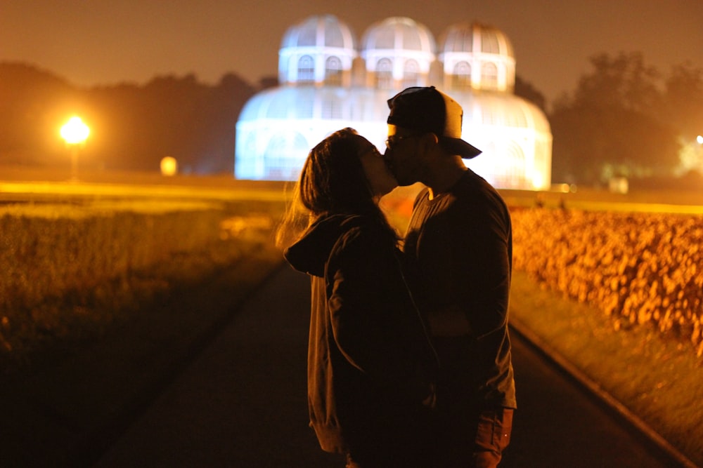 a man and a woman kissing in front of a building