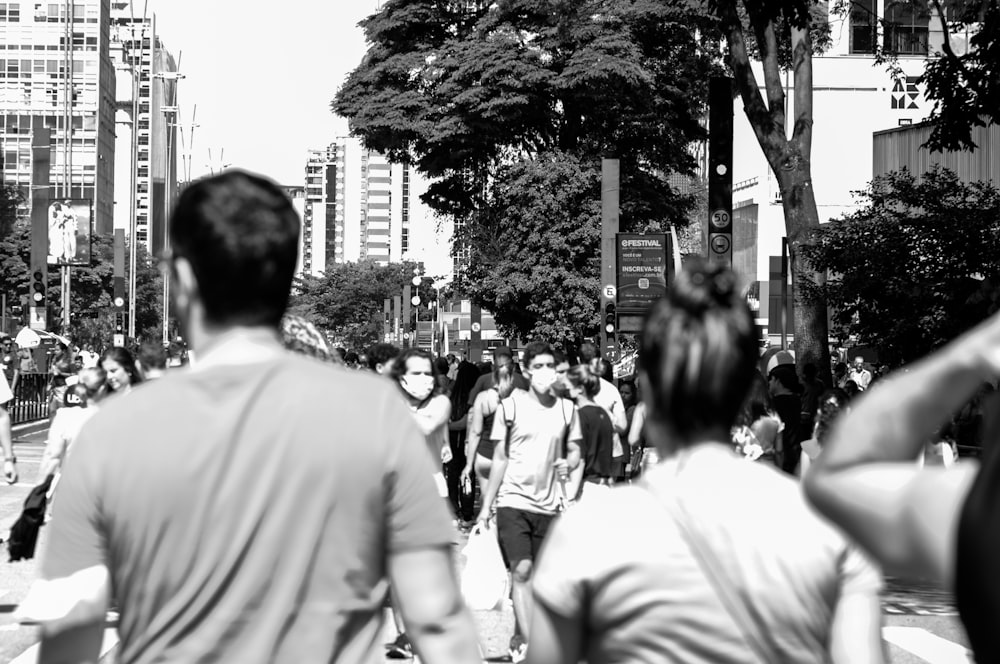 a group of people walking down a street next to tall buildings