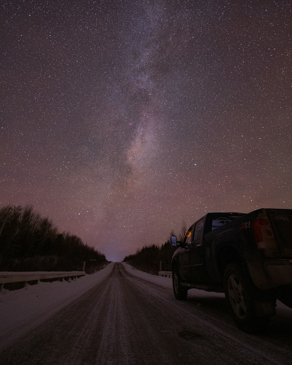 a truck driving down a road under a night sky filled with stars