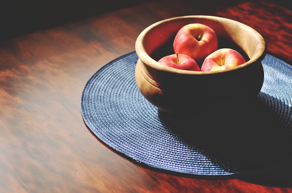 a bowl of apples sitting on top of a wooden table