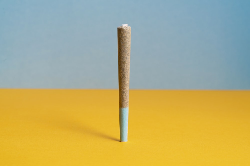 a single cigarette sitting on top of a yellow table