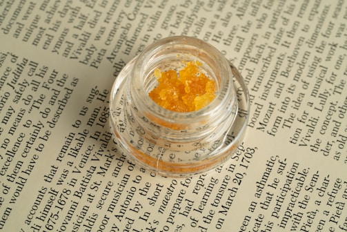 a small jar filled with yellow stuff sitting on top of a book