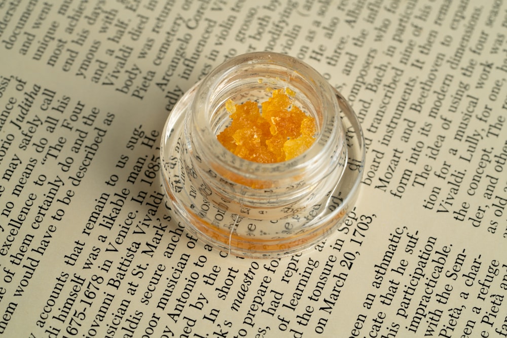 a small jar filled with yellow stuff sitting on top of a book