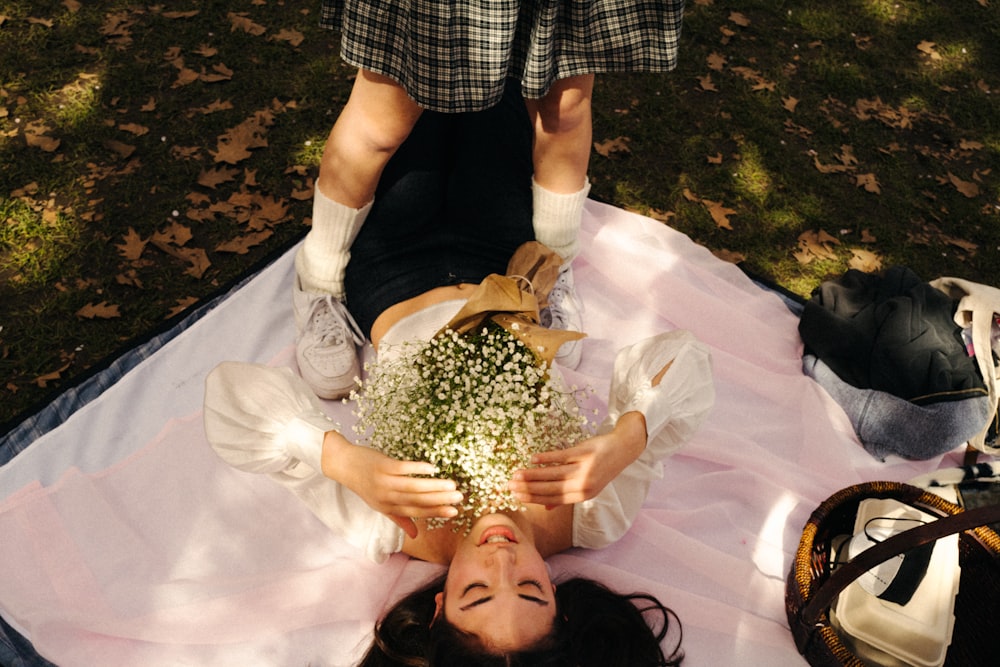 a woman laying on a blanket holding a bouquet of flowers