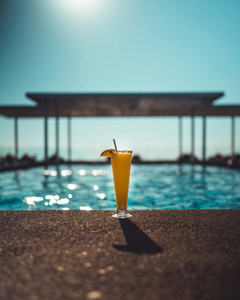 a drink sitting on the edge of a swimming pool