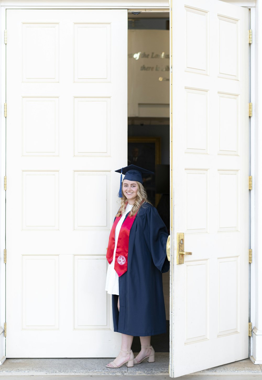 a woman in a graduation gown standing in a doorway