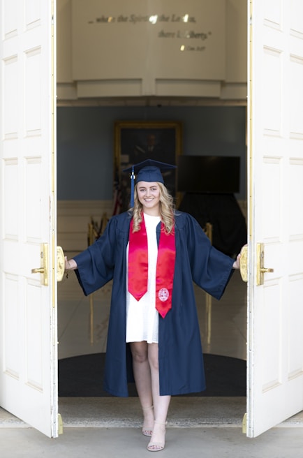 a woman in a graduation gown standing in a doorway