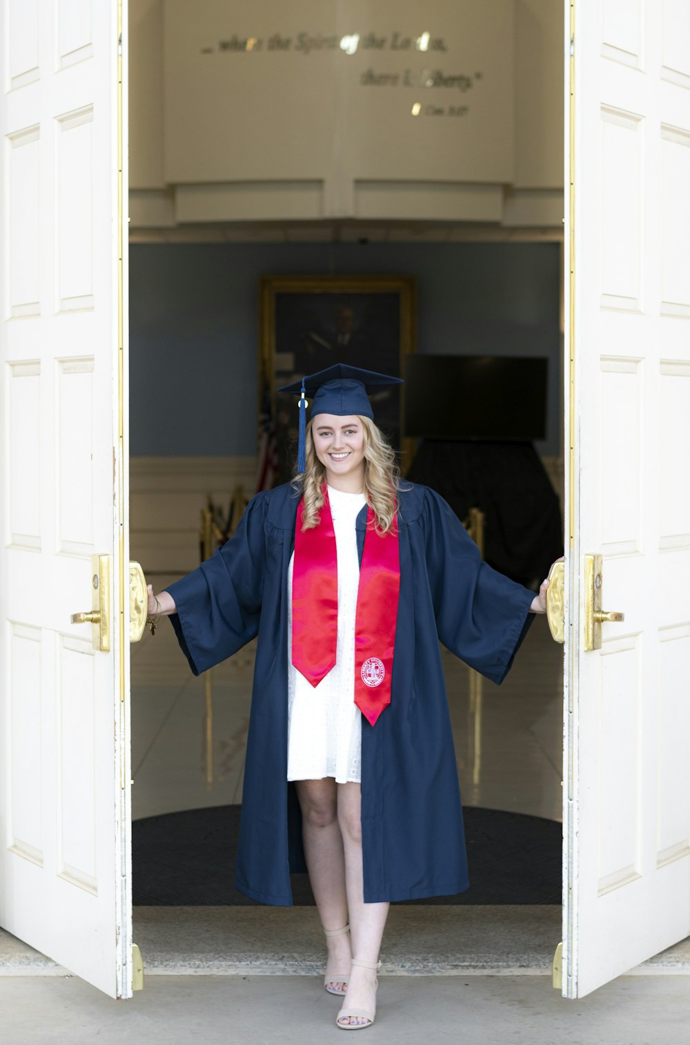 Una mujer con un vestido de graduación parada en una puerta