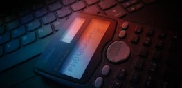 A modern calculator and notes lying on a desk illuminated by a soft purple lamp.