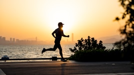a man running on the beach at sunset