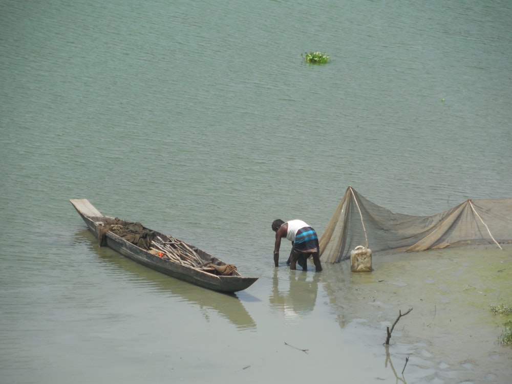 a man standing next to a boat in a body of water