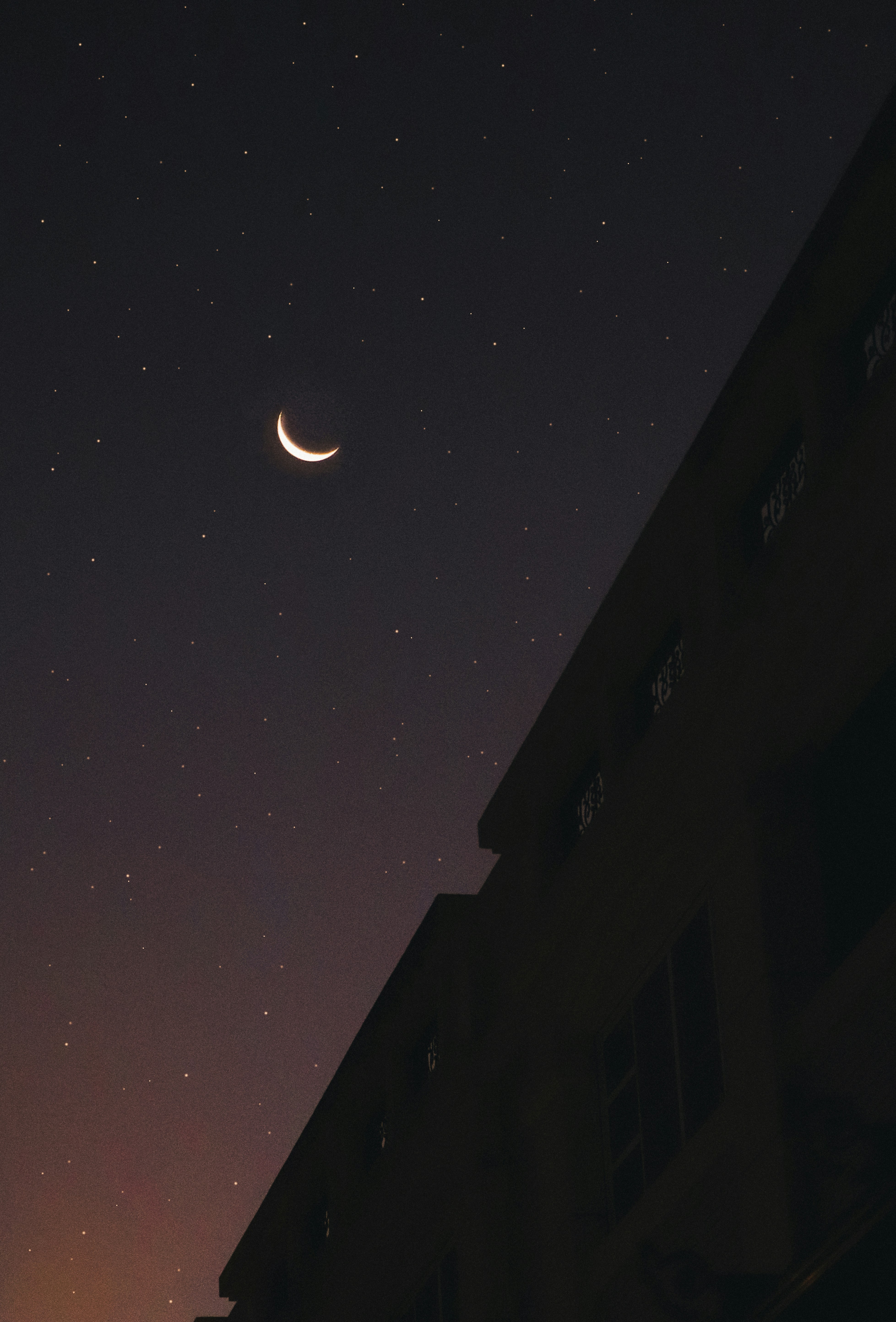 a crescent is seen in the night sky above a building