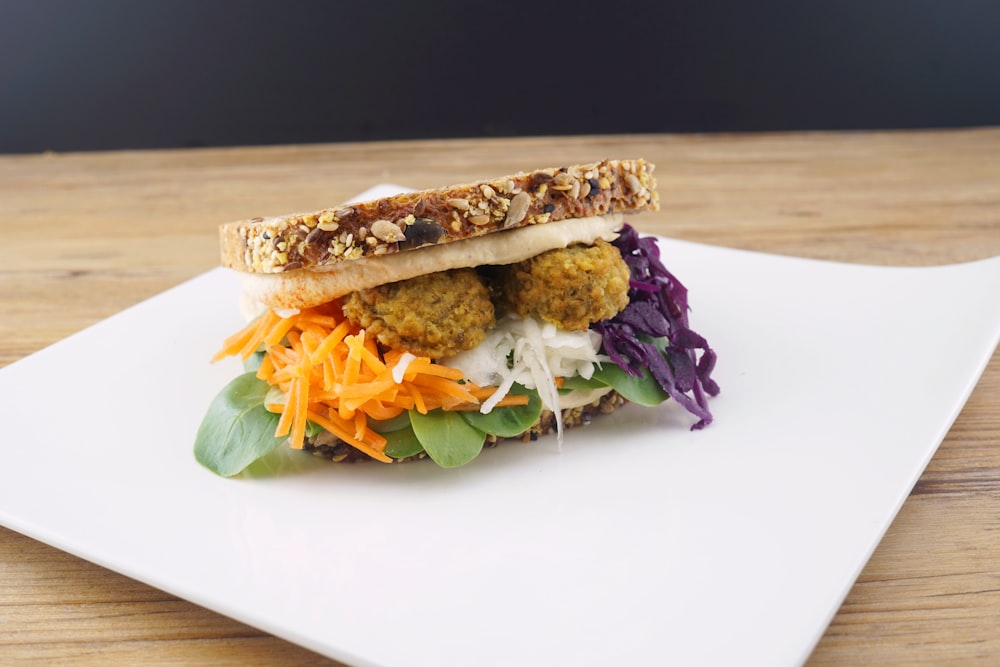 a white plate topped with a sandwich filled with meat and veggies