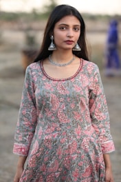 a woman in a dress with a necklace and earrings