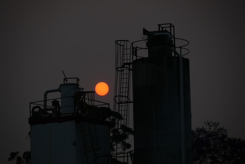 the sun is setting behind two silos
