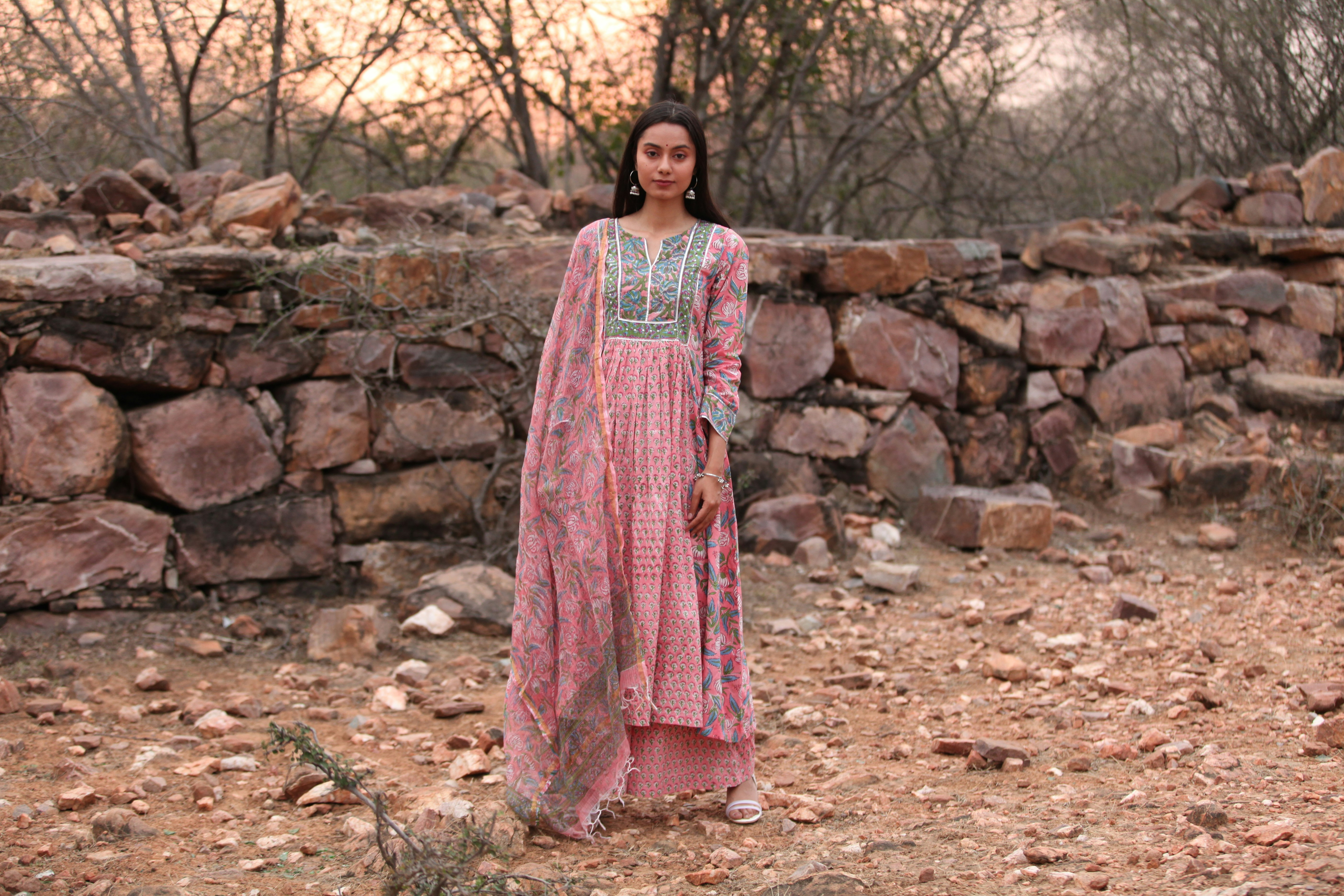 a woman standing in front of a stone wall