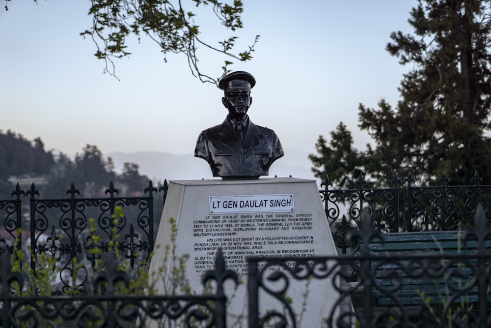 a statue of a man with a hat on top of a sign