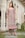 A happy woman wearing a stylish Pakistani suit in a bright outdoor setting.