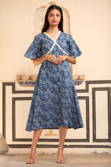 A stylish woman wearing a trendy blue dress from Saubhagya Collection, standing in a bright, modern setting.
