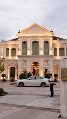 a white car parked in front of a large white building