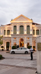 a white car parked in front of a large white building