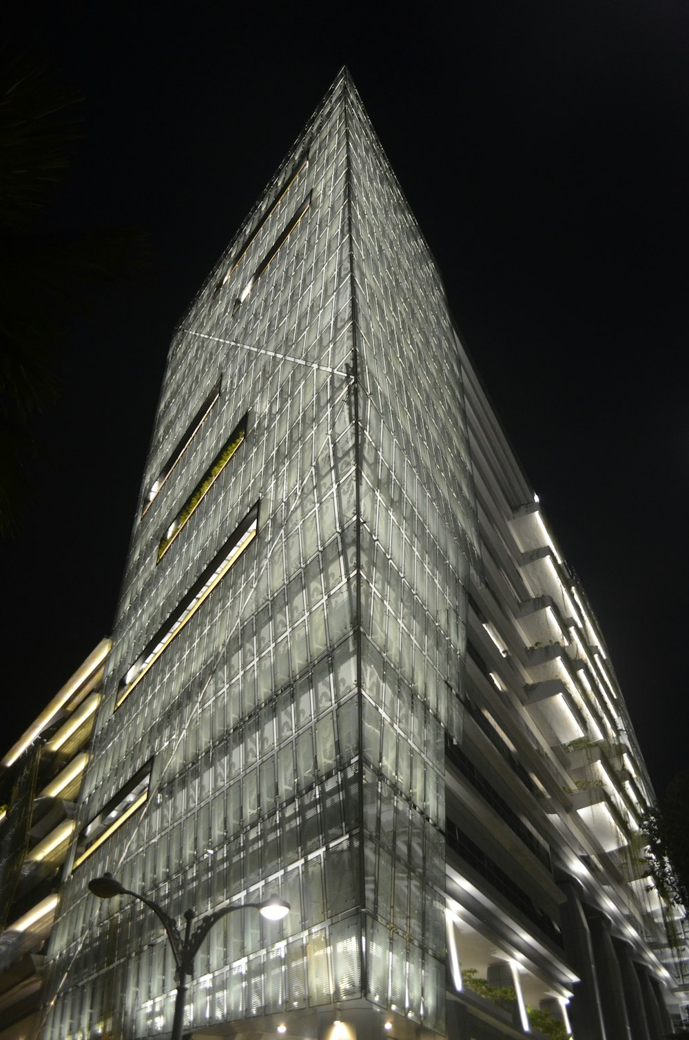 a very tall glass building lit up at night