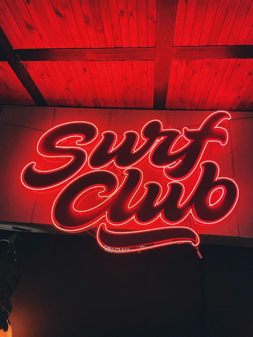 a red neon sign that says surf club