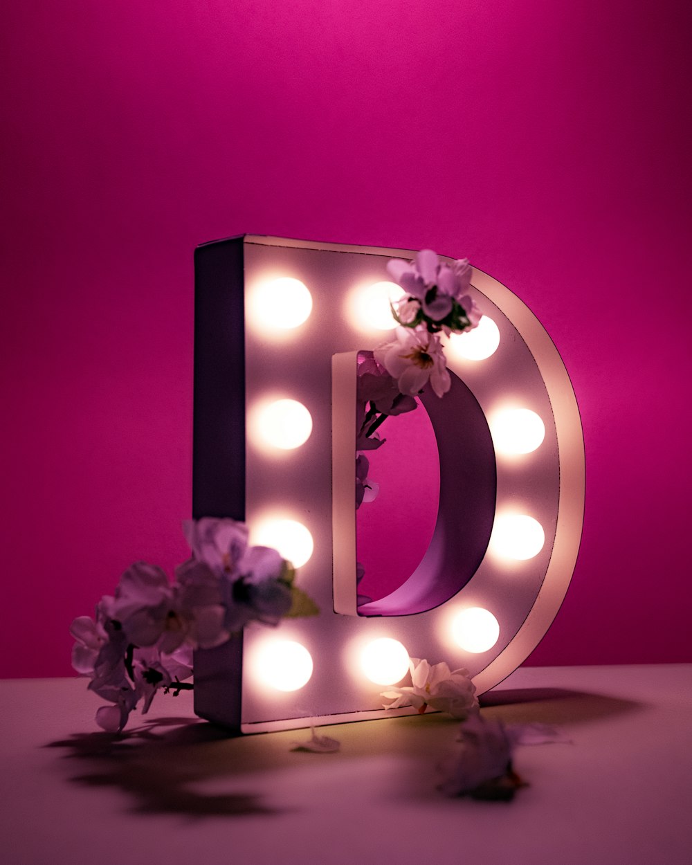 a light up letter with flowers on a table