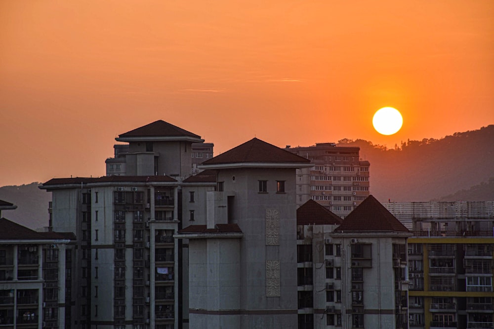 the sun is setting over a city with tall buildings