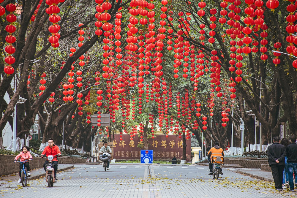 a group of people riding bikes down a street under red lanterns